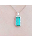 Green emerald pendant necklace on a light pink background