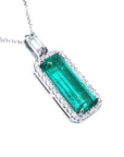 Emerald green gemstone pendant with diamond accents on a white background