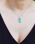 Necklace with a colombian emerald pendant worn by a person in a black top.
