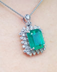 Emerald green gemstone pendant on a silver chain on a skin background