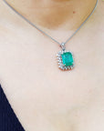 A person wearing a natural emerald pendant on a white gold chain