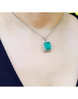 7.78 ct. natural emerald pendant with halo diamonds in 14K white gold, worn on a necklace.