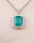 Emerald pendant necklace halo diamond on a white gold chain, skin background
