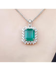 Emerald pendant necklace halo diamond on a white gold chain, skin background