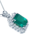 Emerald green gemstone pendant with diamond accents on its right-side perspective view