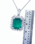 Emerald pendant with diamonds on a white background, accompanied by a ruler for scale.