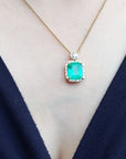 Gold necklace with a natural emerald pendant on a woman's neck.