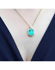 7.09 ct. natural emerald pendant necklace with halo diamonds on an 18K yellow gold chain.
