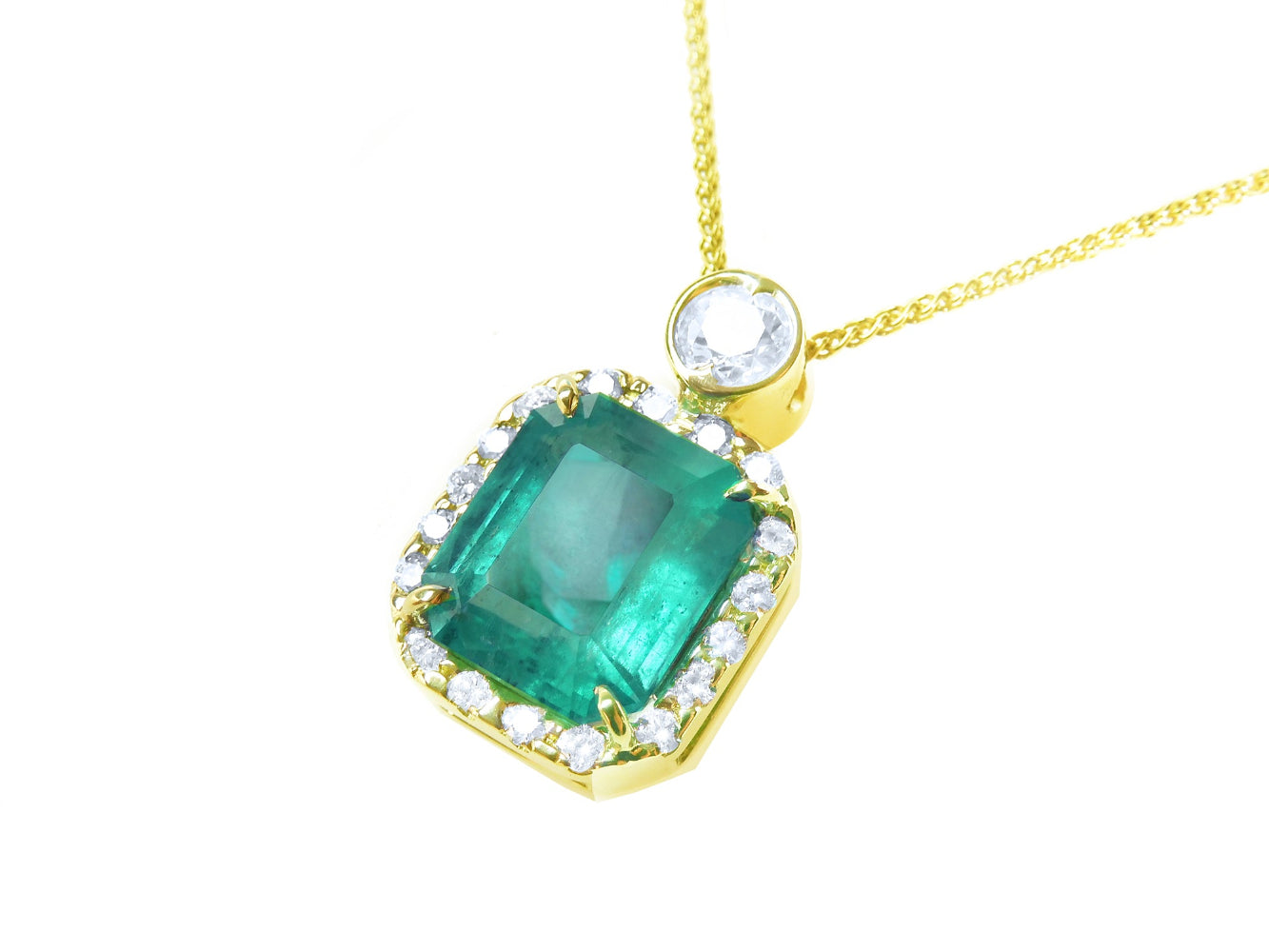 Topside profile of a colombian square emerald into a halo diamond handcrafted in 18k yellow gold.