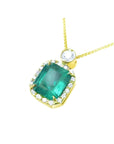 7.09 ct emerald pendant necklace with diamond halo and round diamond accent on 18K yellow gold chain.