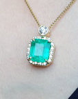 Gold necklace with a square emerald pendant on a skin background.