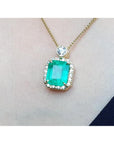Gold necklace with a square emerald pendant on a skin background.