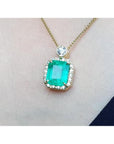 18K yellow gold necklace with a large emerald-cut emerald pendant surrounded by a halo of diamonds.