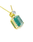 18K yellow gold emerald pendant necklace with a halo of diamonds on a delicate chain.