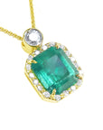 A 18k yellow gold pendant with a natural emerald and diamond accents on a topside view.
