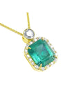 A 18k yellow gold pendant with a natural emerald and diamond accents on a topside view.