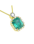 A 18k yellow gold pendant with a natural emerald and diamond accents on a topside view.