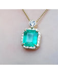 A square natural colombian emerald in a halo diamond pendant made in 18k yellow gold topside view.