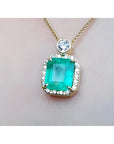 A square natural colombian emerald in a halo diamond pendant made in 18k yellow gold topside view.