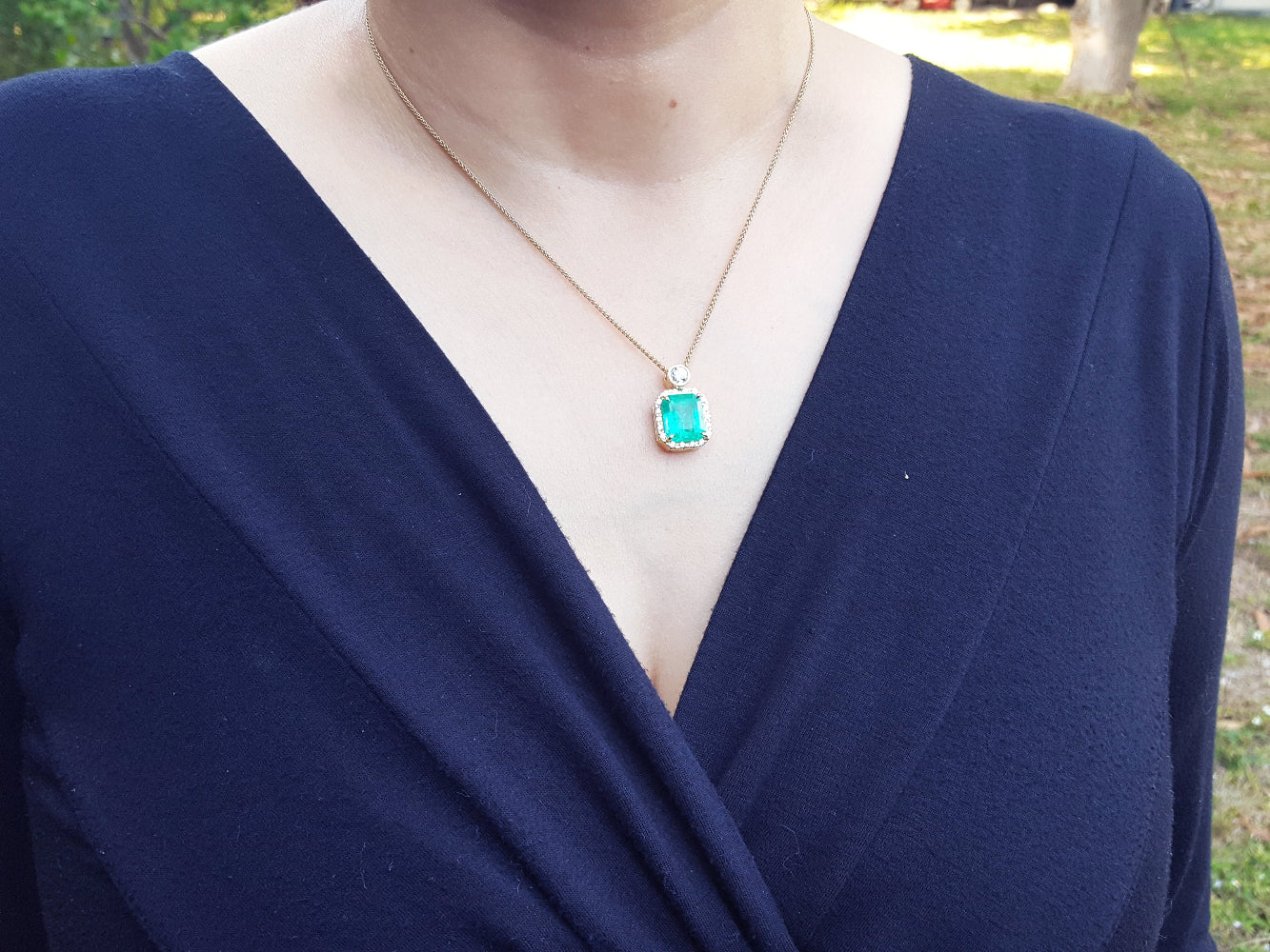 Navy blue top with a necklace featuring a natural emerald pendant.