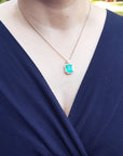 Navy blue top with a necklace featuring a natural emerald pendant.