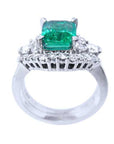 The white gold matching band with diamonds lateral profile in front of the emerald engagement ring.