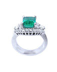 The white gold matching band with diamonds lateral profile in front of the emerald engagement ring.
