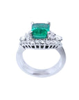 Emerald-cut vivid bluish green emerald ring in white gold, flanked by diamonds.