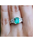 A real Colombian emerald and matching band ring with diamonds white gold on a finger.
