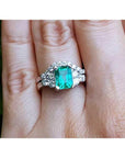 A real Colombian emerald and matching band ring with diamonds white gold on a finger.