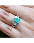 Emerald-cut vivid bluish-green emerald ring with matching diamond band in 14K white gold.