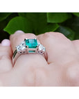 Emerald-cut natural emerald ring with three diamonds on each side, set in 14K white gold.