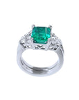 Emerald-cut vivid bluish green emerald ring with diamond accents and matching white gold band.