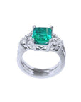 Emerald-cut vivid bluish green emerald ring with diamond accents and matching white gold band.