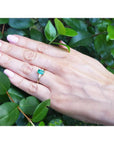 1.05 ct. natural emerald ring with side baguette diamonds in 14K yellow gold on a hand.