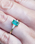 GA yellow gold ring with a real colombian emerald on a person's finger.