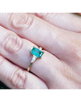 GA yellow gold ring with a real colombian emerald on a person's finger.