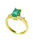 A 14k yellow gold ring with a genuine emerald side profile on a white background.