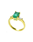 A 14k yellow gold ring with a genuine emerald side profile on a white background.
