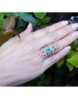 Sterling silver ring with oval natural emerald, CZ halo, and intricate filigree design on a hand.