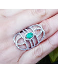 Sterling silver ring with a natural oval emerald center and CZ halo, featuring an intricate filigree design.