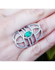Sterling silver ring with a natural oval emerald center and CZ halo, featuring an intricate filigree design.