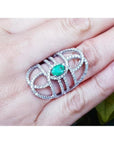 Sterling silver ring with a natural oval emerald center and CZ halo, featuring an intricate filigree design.