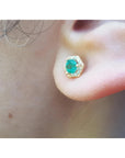 Hexagon emerald and diamond stud earring in 14K yellow gold, worn on an ear.