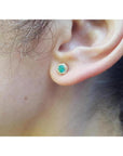 Hexagon emerald and diamond stud earring in 14K yellow gold on an ear.