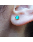 Girls' 0.32 ct. round natural Colombian emerald stud earring in 14K gold, worn on an ear.