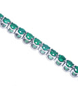 A tennis bracelet with round cut natural colombian emeralds in 14k white gold showing the side profile view.