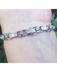 White gold bracelet with princess cut diamonds, worn on a wrist.
