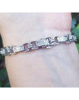 White gold bracelet with princess cut diamonds, worn on a wrist.