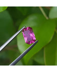 1.38 ct GIA certified loose natural purplish pink sapphire, fancy emerald-cut, held by tweezers.